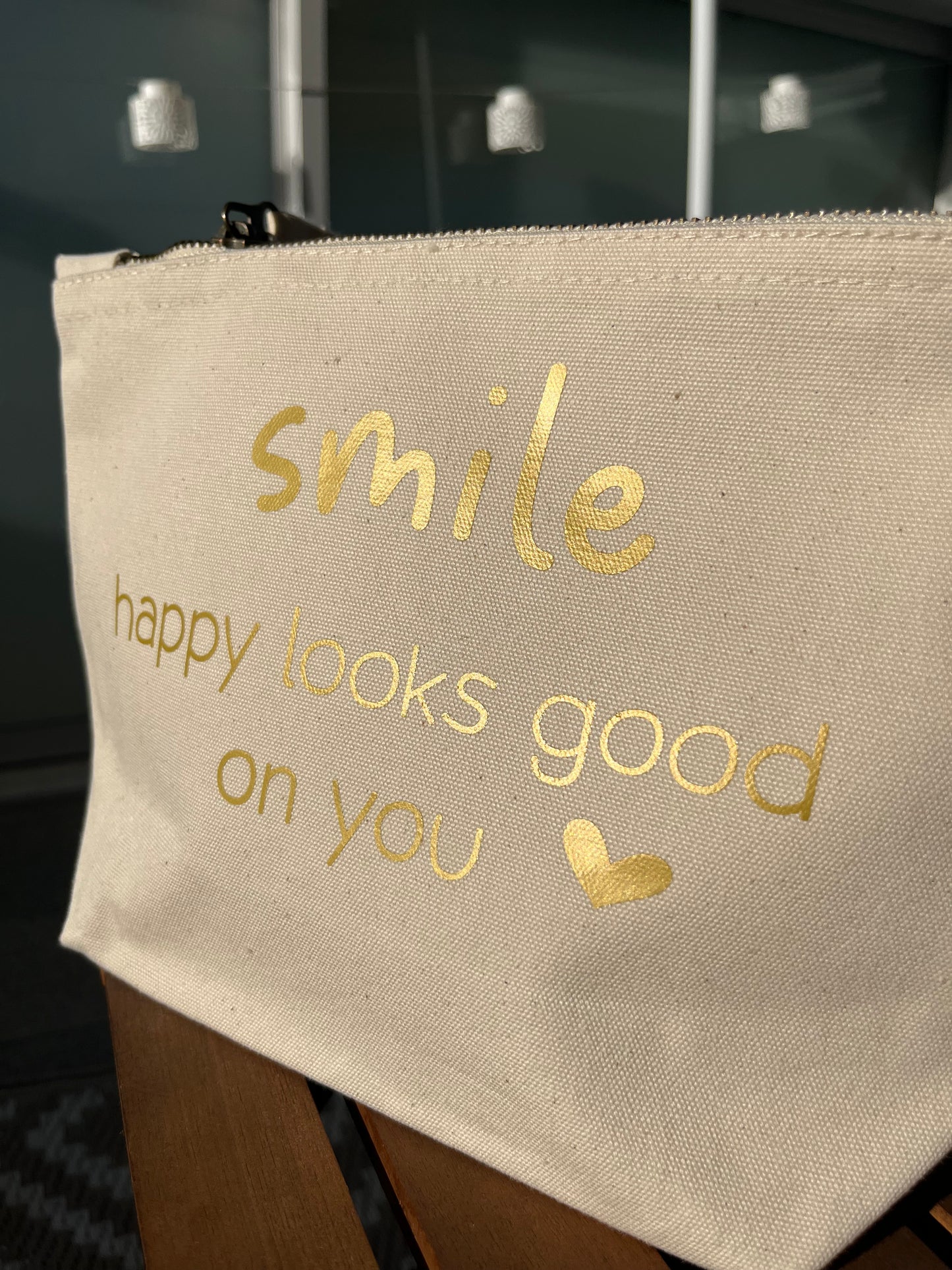 Helle Tasche mit Reißverschluss mit goldener Aufschrift SMILE