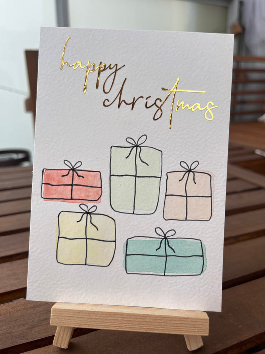 Weihnachtskarte mit Geschenken und goldener Schrift