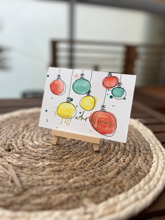 Weihnachtskarte mit Kugeln und goldener Schrift