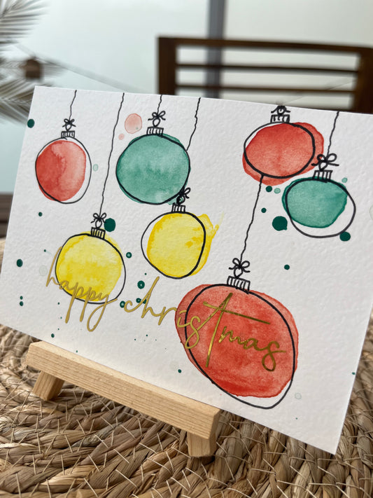 Weihnachtskarte mit Kugeln und goldener Schrift