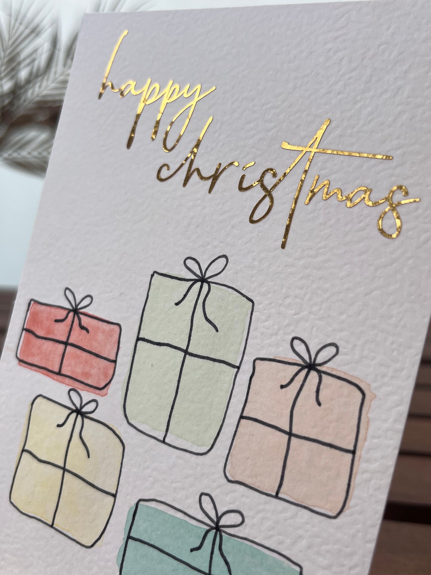 Weihnachtskarte mit Geschenken und goldener Schrift