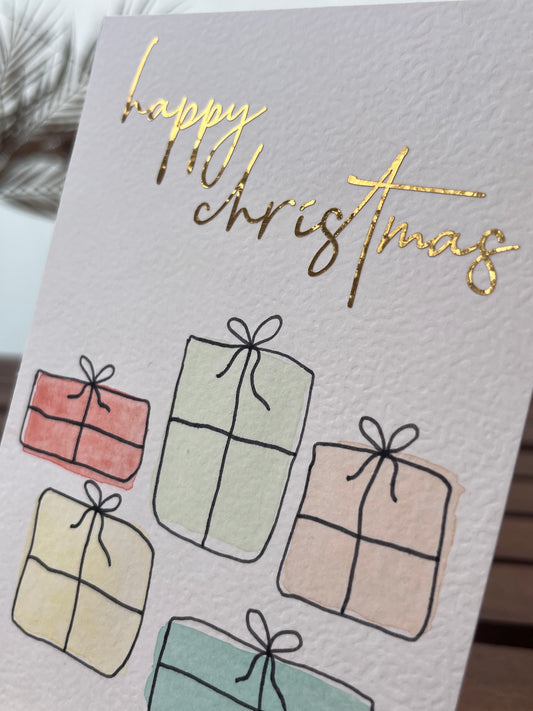 Weihnachtskarte mit Geschenken und goldener Schrift